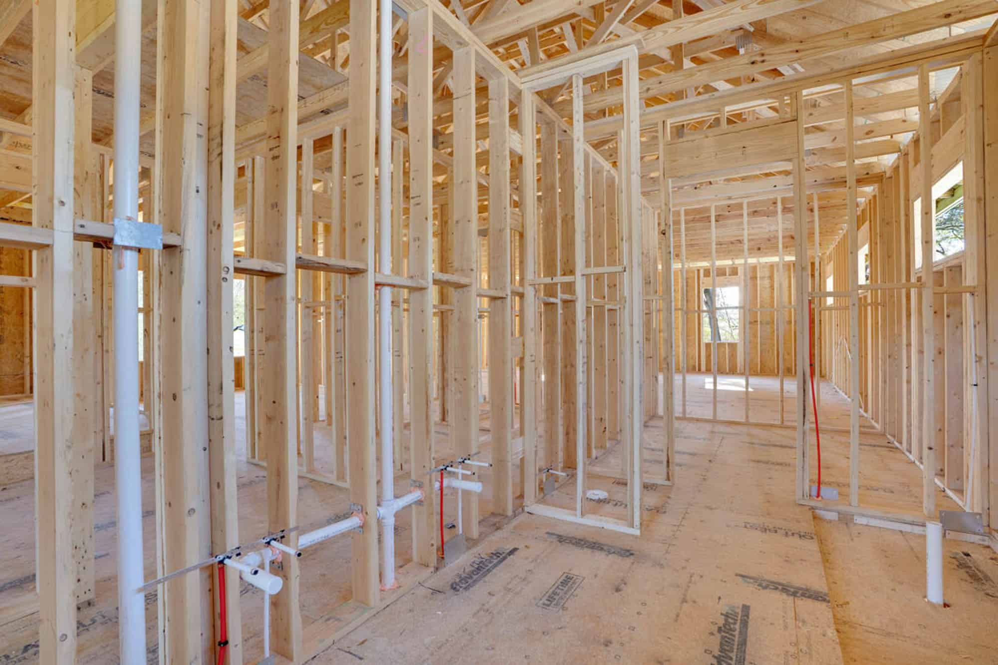 Framing of a custom home under construction, showcasing wooden studs and structural framework.