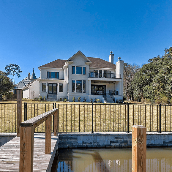 Elegant custom home with water view, large windows, and spacious balcony.