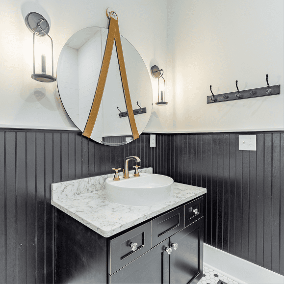 Modern bathroom vanity with marble countertop and black cabinetry.